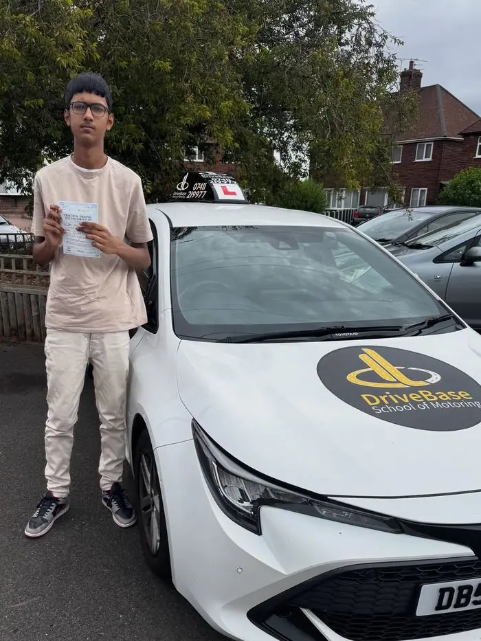 Aqib with their driving test pass certificate beside the DriveBase car