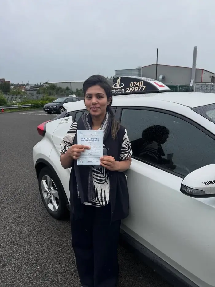 Eram with their driving test pass certificate beside the DriveBase car