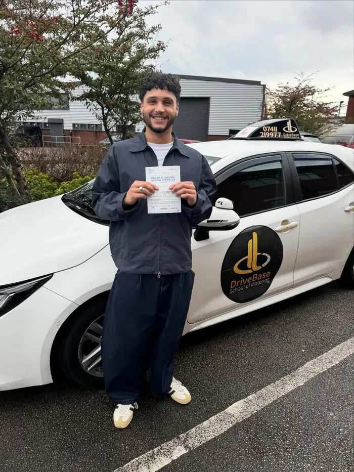 Kieran with their driving test pass certificate beside the DriveBase car