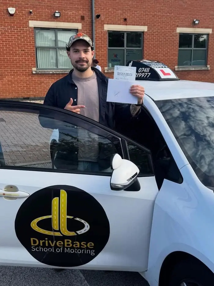 Oskar with their driving test pass certificate beside the DriveBase car