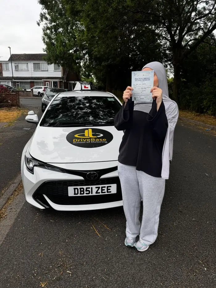 Sara with their driving test pass certificate beside the DriveBase car