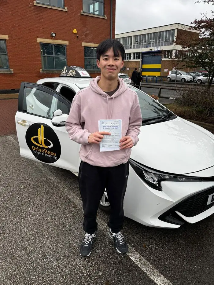 Brian with their driving test pass certificate beside the DriveBase car
