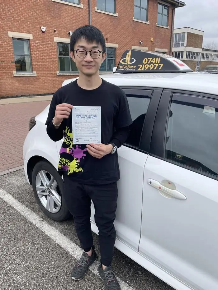 Gary with their driving test pass certificate beside the DriveBase car