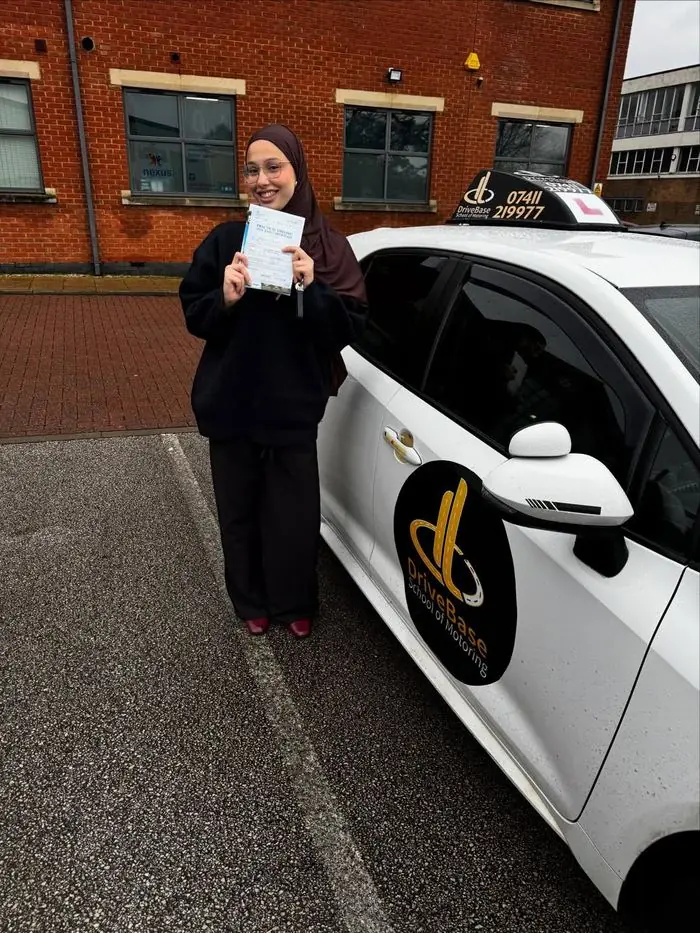 Rayan with their driving test pass certificate beside the DriveBase car