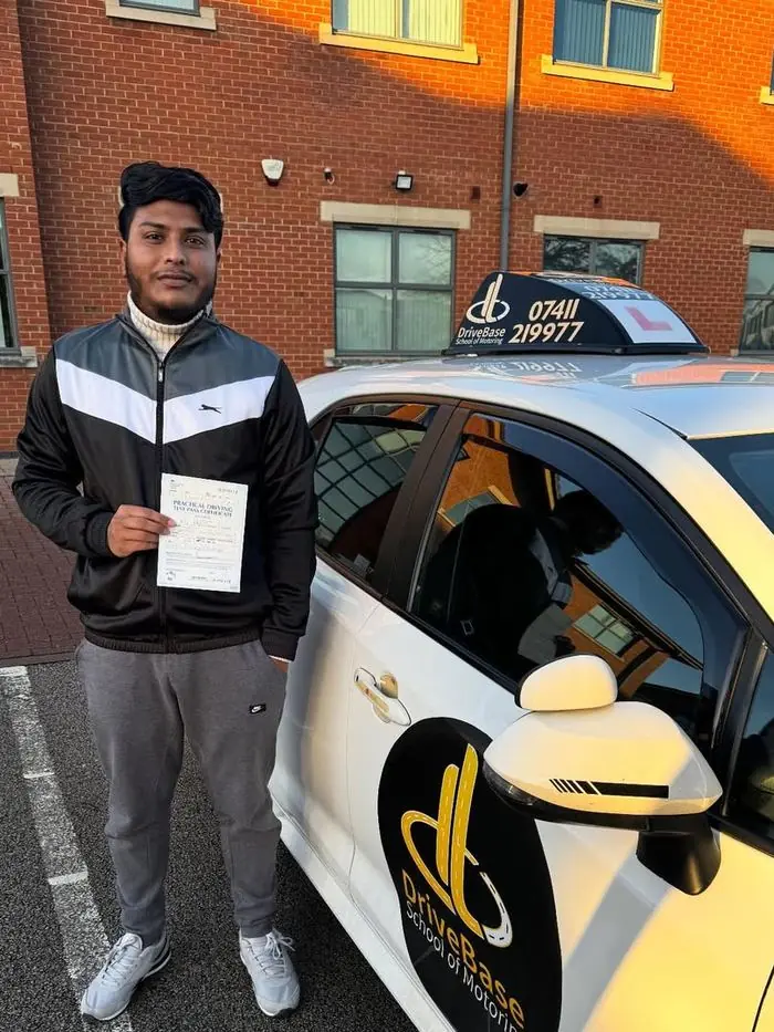 Tanvir with their driving test pass certificate beside the DriveBase car