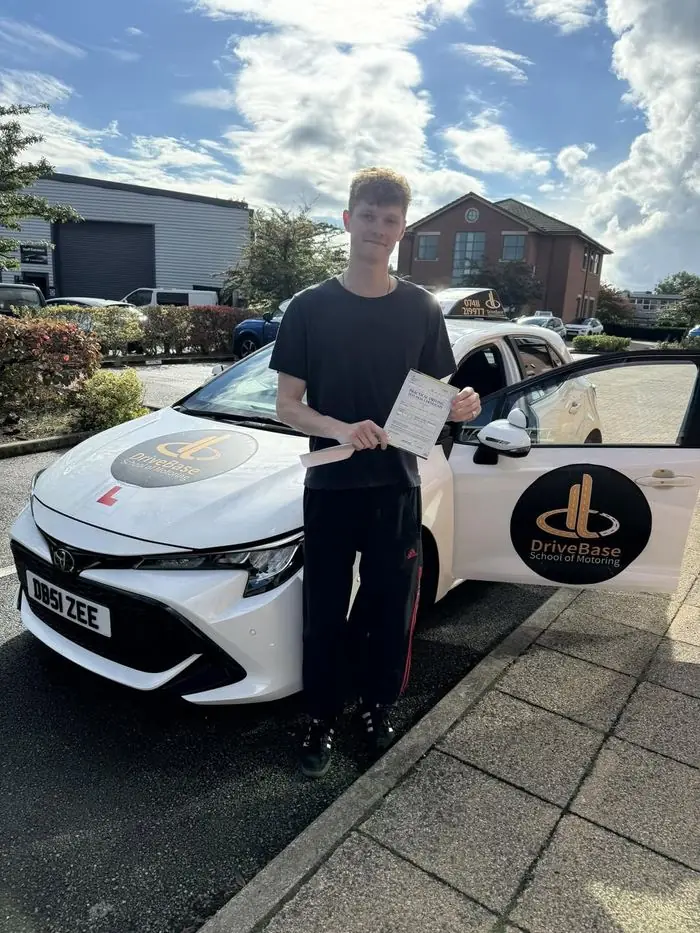 Tom with their driving test pass certificate beside the DriveBase car